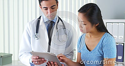 Hispanic doctor talking with patient with test results on tablet