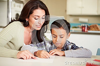 Hispanic Mother Helping Son With Homework At Table