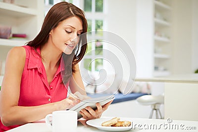 Hispanic Woman Using Digital Tablet In Kitchen