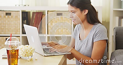 Hispanic woman using laptop on coffee table