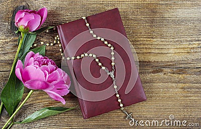 Holy Bible, rosary and lush pink peonies