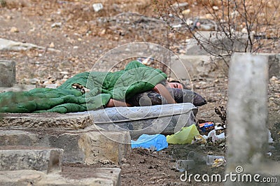 Homeless Poor Man Sleeps in a Graveyard