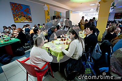 Homeless and unhealthy people sit around tables with food at the Christmas charity dinner for the homeless