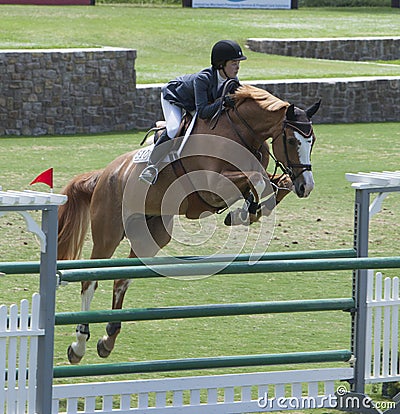 Girl flys on her Horse Over a Jump