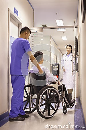 Hospital Staff Pushing Patient In Wheelchair