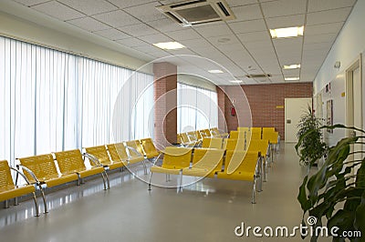 Hospital waiting area with yellow metallic chairs.