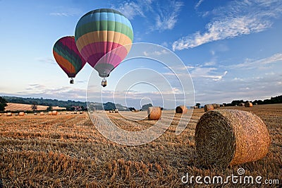 Hot air balloons over hay bales sunset landscape