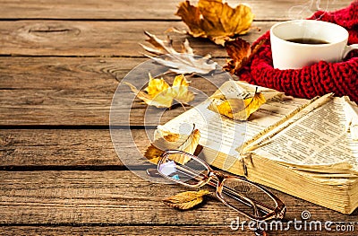 Hot coffee, book, glasses and autumn leaves on wood background