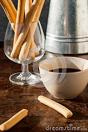 Hot coffee and bread sticks on the wooden table