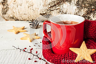 Hot winter tea in a red mug with christmas cookies
