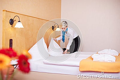 Housekeeper Making Bed In Hotel Room