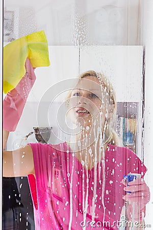 Housewife with protective glove washing the window glass