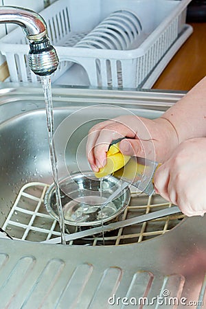Housewife washing dishes in sink