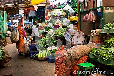 INDIA: Vegetable seller reads a newspaper and waits for the customers on the old city market