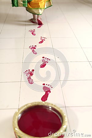 Indian Hindu Bride entering groom s home after wedding with her foot marks in red kum kum paste.