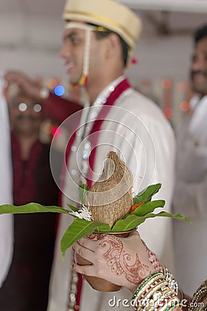 Indian Hindu Groom s sister with coconut in her hands at the ritual of exchanging garland in maharashtra wedding.