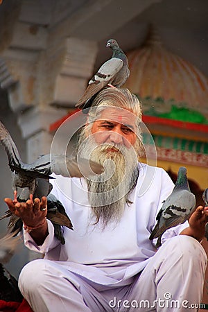 Indian man feeding pigeons near holy lake, Pushkar, India