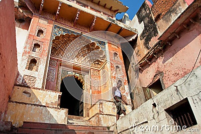 Indian man walk past old colorful temple gate
