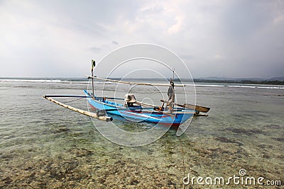 small Indonesian fishing boat moored on a coral reef in Sumatra.