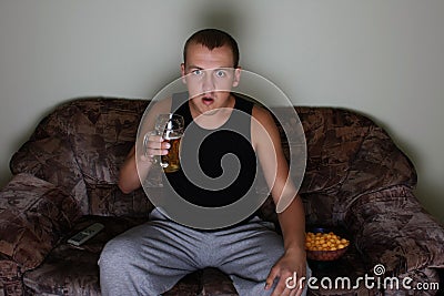 Interested man watching tv with beer and chips