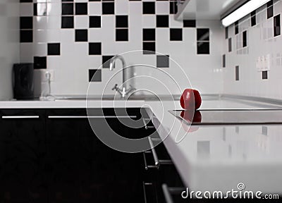 Interior of black and white kitchen with red apple