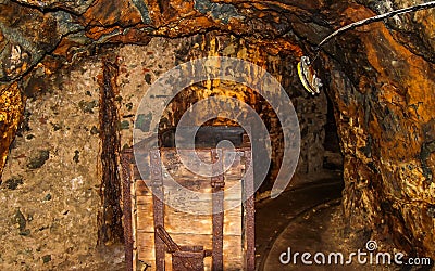 Interior of underground mine passage with rails, light and carriage