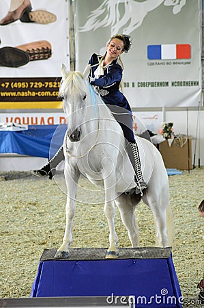 International Horse Show. Woman jockey in blue dress Female rider on a white horse.