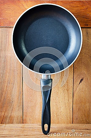 Iron frying pan and wooden wall background .