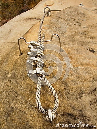 Iron twisted rope fixed in block by screws snap hooks. Detail of rope end anchored into sandstone rock