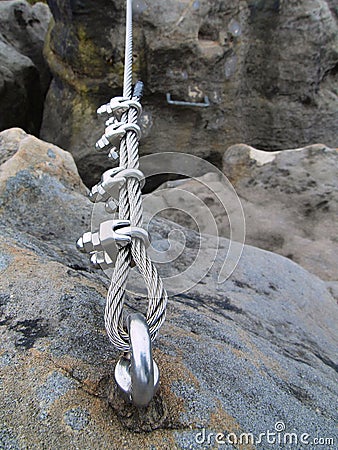 Iron twisted rope fixed in block by screws snaphooks. Detail of end of the anchored rope