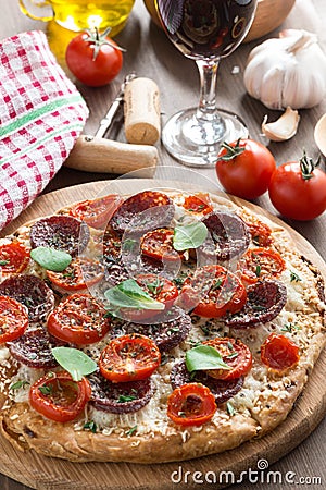 Italian food - pizza with salami and tomatoes, glass of wine