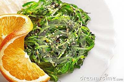 Japanese cuisine. Seaweed salad with orange in white plate