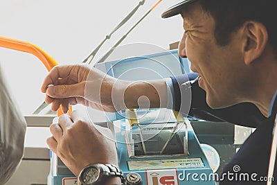 Japanese public bus driver gives the change to a passenger