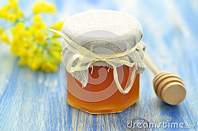 Jar of delicious honey in a jar with rapeseed flowers