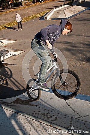 Joung red haired boy jumps with his BMX Bike at the skate park