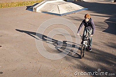 Joung red haired boy jumps with his BMX Bike at the skate park