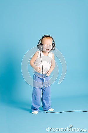 Joyful boy listening music at cord headphones