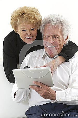 Joyful elderly couple with tablet