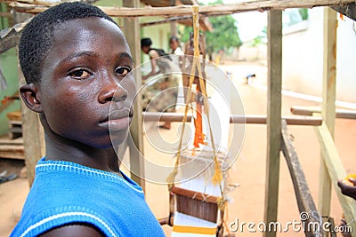 African boy in his outdoor cloth weaving shop
