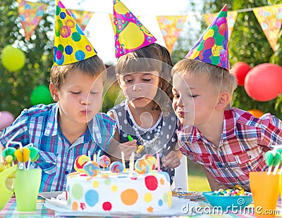 Kids at birthday party blowing candles on cake