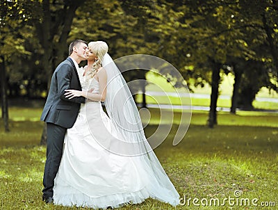 Kissing wedding couple in a park