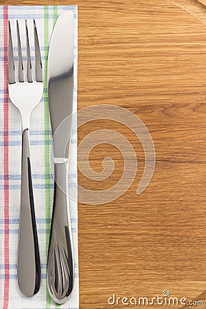 Knife and fork at napkin on wood