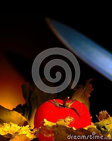 Knife strikes a tomato resting on a bed of lettuce