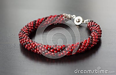 Knitted bracelet from beads of two shades of red color