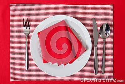 Laid table - fork and spoon laid on red cloth and white plate