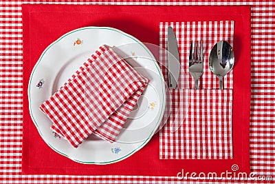 Laid table - fork and spoon laid on red cloth and white plate