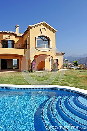 Large yellow sunny spanish villa with pool and blue sky