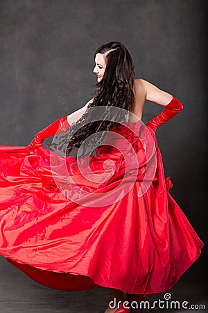 Latino Woman with long hair in red waving dress dancing in action with flying fabric