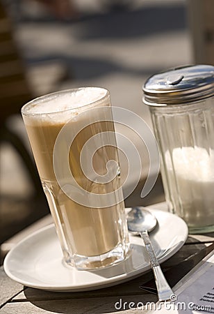 Latte macchiato and sugar dispenser on table