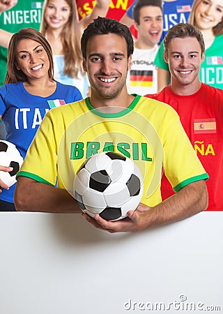 Laughing brazilian soccer fan with other fans behind signboard